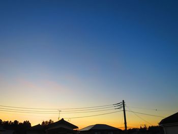 Low angle view of silhouette electricity pylon against clear sky