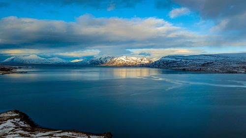 Scenic view of sea by snowcapped mountain against sky