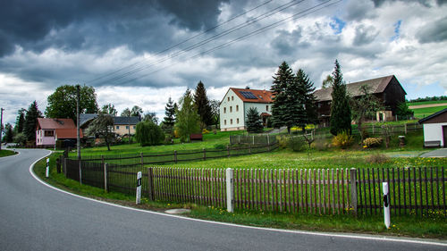 Road by buildings against sky