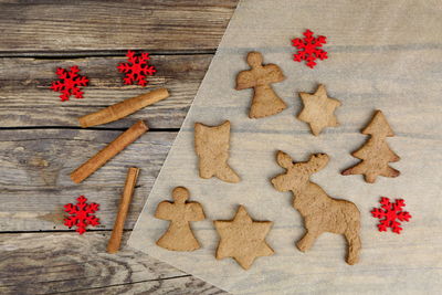 High angle view of christmas decorations with cookies and cinnamons on wooden table