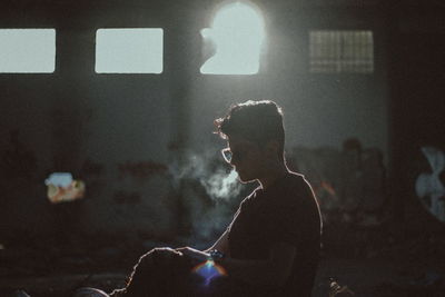 Side view of man smoking in room