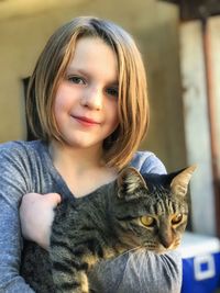 Portrait of smiling young woman with cat at home