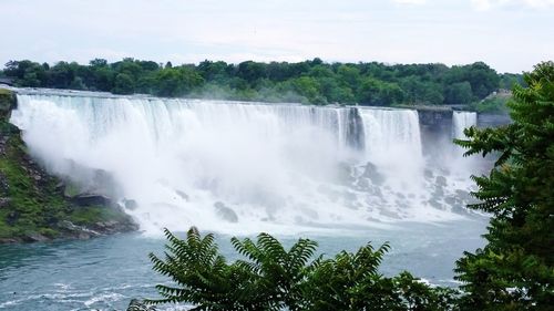 Scenic view of waterfall in forest against sky