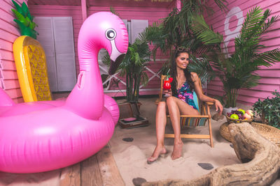 Full length of woman sitting with pink balloons