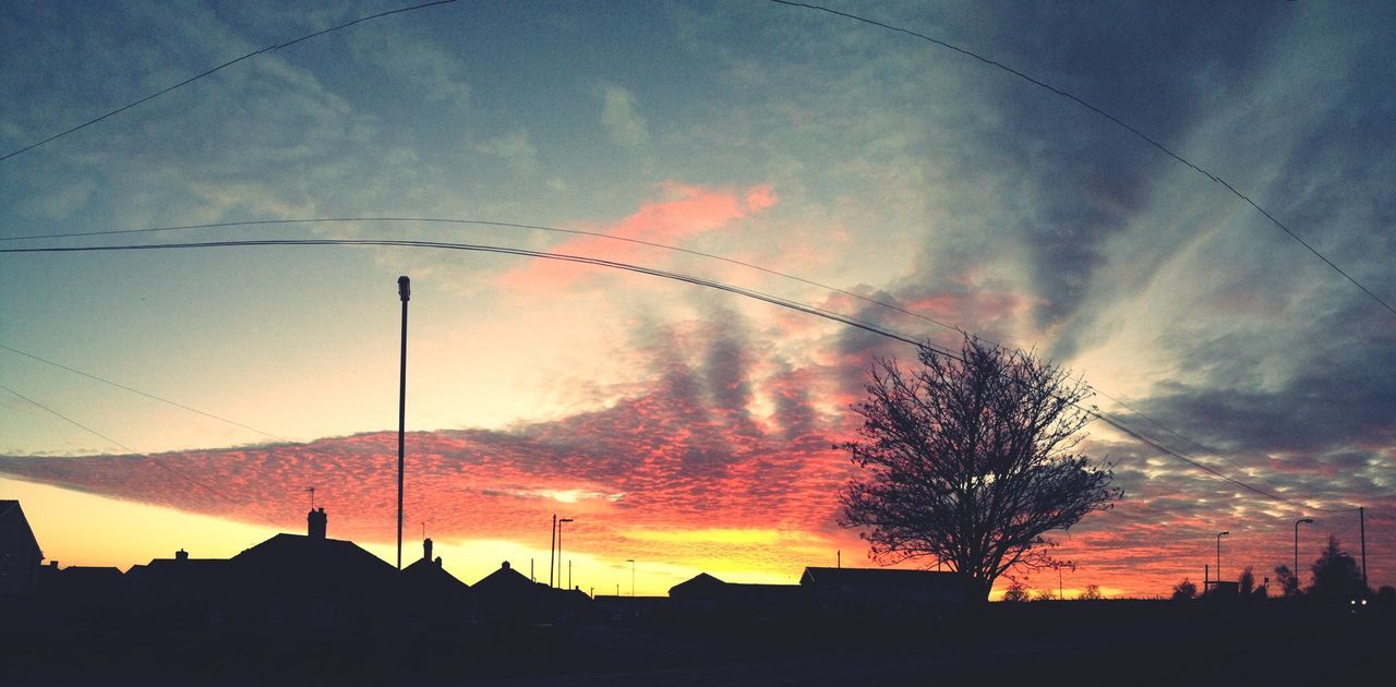 sunset, silhouette, building exterior, architecture, built structure, sky, low angle view, cloud - sky, city, orange color, building, cloud, power line, street light, house, cloudy, dusk, outdoors, dramatic sky, no people