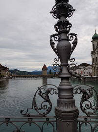 Close-up of metal structure by river against sky in city