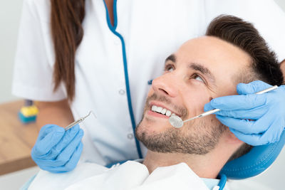 Dentist examining smiling patient at clinic