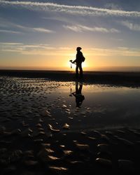 Silhouette man on beach against sky during sunset