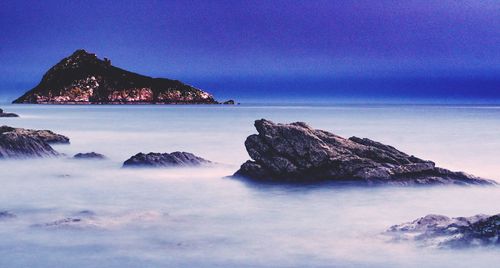 Scenic view of sea and mountains against clear blue sky