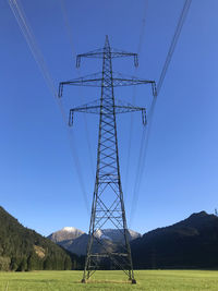 Low angle view of electricity pylon on field against clear sky