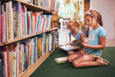 Schoolgirls looking for book for reading in school library. choosing books. doing homework