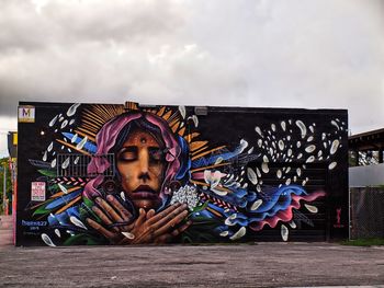 Graffiti on wall against cloudy sky