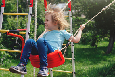 Happy girl swinging on a swing at the playground on a warm sunny day