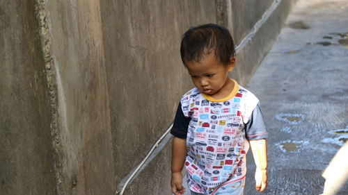 High angle view of cute baby boy standing by wall