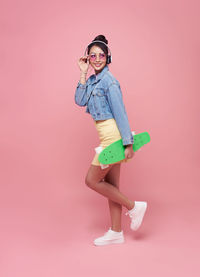 Portrait of woman wearing sunglasses standing against pink background