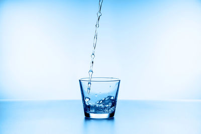 Close-up of drinking glass in water against blue background