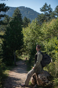 Hiker with backpack siting at footpath in forest