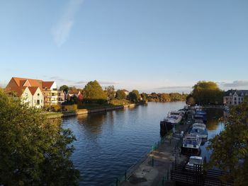 Houses by river and buildings against sky