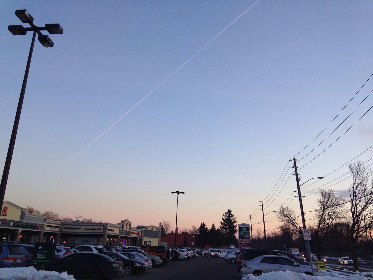 transportation, car, land vehicle, mode of transport, clear sky, street light, street, road, traffic, parking, on the move, sky, blue, travel, power line, built structure, city, sunset, stationary, outdoors