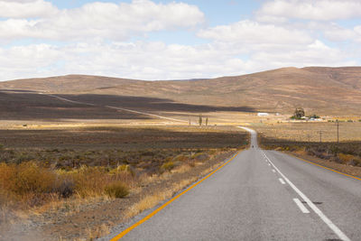 Road leading towards mountains against sky