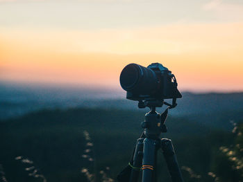 Close-up of camera on land against sky during sunset