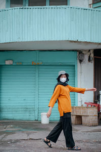 Full length of woman wearing mask walking outdoors