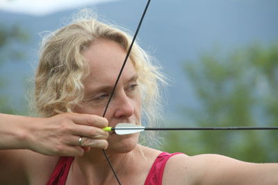 Close-up of mature woman aiming archery