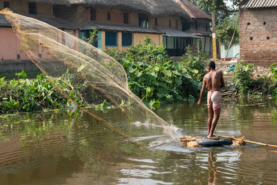 Full length of shirtless man standing in lake