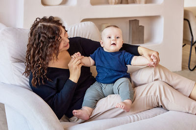 Siblings sitting on sofa at home