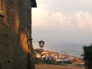 Buildings by sea against sky