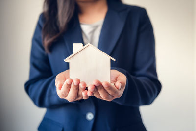 Midsection of woman holding paper while standing against house