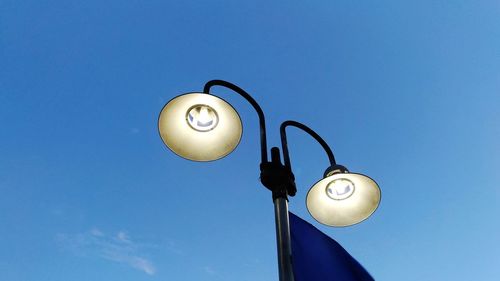 Low angle view of illuminated street light against clear blue sky