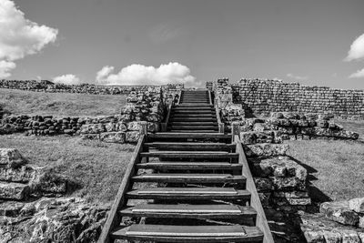 Staircase leading to wall against sky