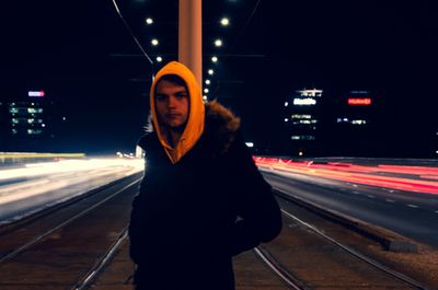 Portrait of man standing on road at night