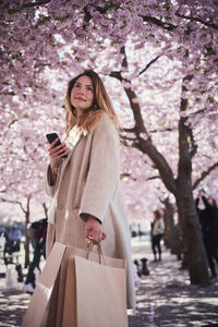 Young woman standing under cherry blossom