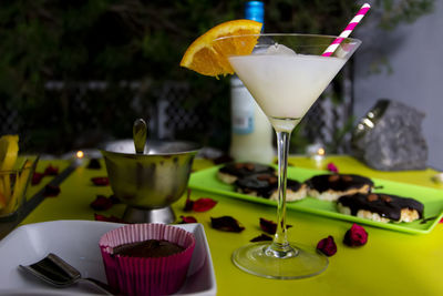 Happy romantic couple celebrating, holding glasses of cocktails with fruits and drinking straws. 