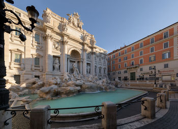 Fountain in city against clear blue sky