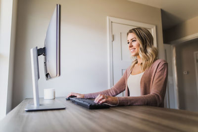 Woman using phone while sitting on table at home