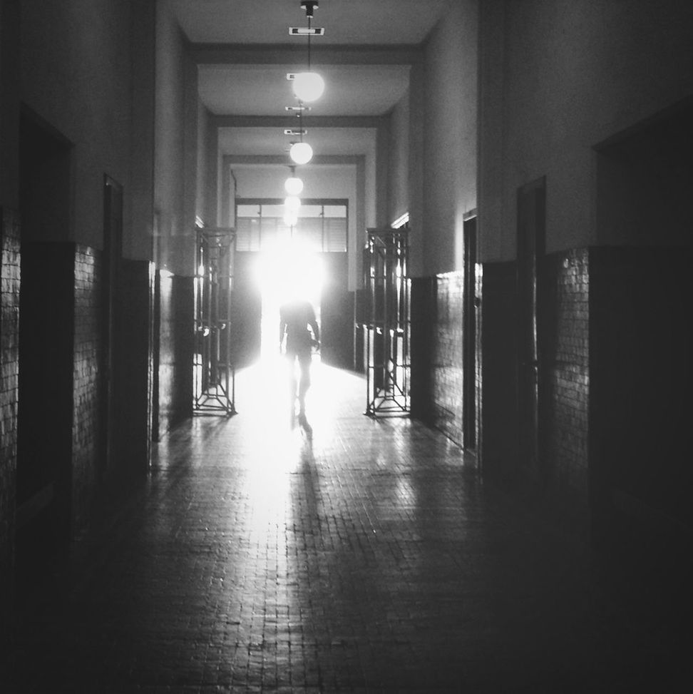 indoors, illuminated, architecture, built structure, corridor, men, lifestyles, flooring, the way forward, lighting equipment, walking, full length, building, person, leisure activity, reflection, ceiling, empty