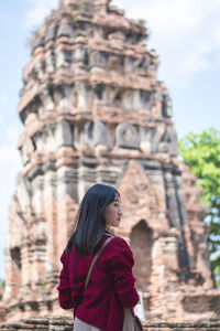 Rear view of young woman standing against historic temple