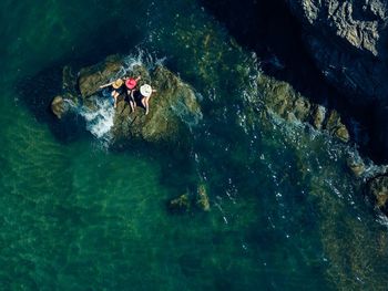 High angle view of women sitting on rock amidst sea