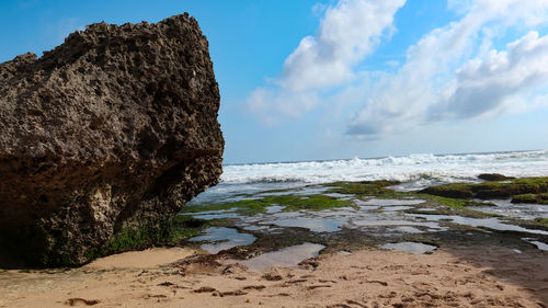 Rock formation on beach against sky