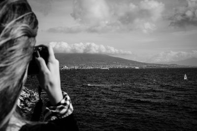 Close-up of woman photographing sea against sky