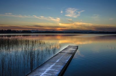 Pier over lake against sky during sunset