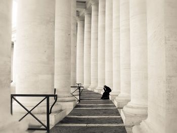 Mid distance view of man sitting by columns at colonnade