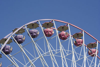 Low angle view of ferris wheel against clear blue sky