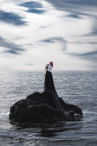 View of bird on rock by sea against sky