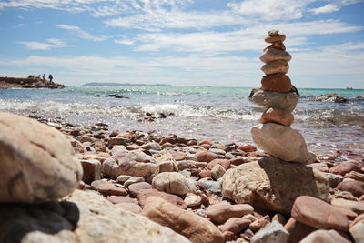 Stack of stones on beach against sky