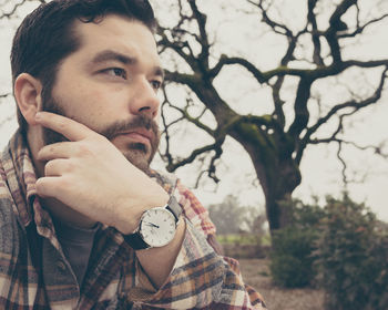 Man looking away against bare tree