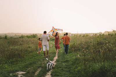 Happy family and children run on meadow with a kite in the summer on the nature.